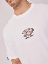 Remera blanca de algodón con estampa en la espalda con el logo de Rusty y la leyenda 'Since chasing surf records 1985'.