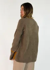 Sweater de punto color bordó con cuello en V, manga larga con puños acanalados y detalle de franja en contraste. Presenta un diseño holgado con aberturas laterales.