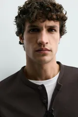 Camiseta de manga corta con cuello panadero y cierre frontal de tres botones. Presenta una textura acanalada y un corte regular fit.