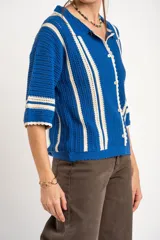 Cardigan oversize de crochet de algodón peinado, color azul con rayas verticales blancas, cuello tipo polo y cierre frontal de botones.