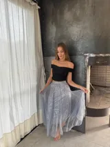 Pollera midi de tul gris con lentejuelas plateadas brillantes. Presenta una cintura elástica y una caída amplia con movimiento.