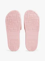 Ojotas tipo slide color rosa pálido, con pala ancha que presenta un patrón de monograma TH en relieve. Cuentan con una pequeña insignia metálica dorada del monograma TH en la tira y el logo de Tommy Hilfiger en relieve en la entresuela.