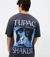 Remera de corte relajado color gris oscuro, con cuello redondo y manga corta. Presenta una estampa frontal pequeña en color blanco con el logo de Tupac.