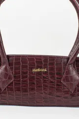 Cartera tipo baguette color negro con textura efecto cocodrilo, diseño alargado, doble asa de mano y cierre superior.