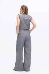 Pantalón de pierna amplia y tiro alto, confeccionado en tejido a rayas con una mezcla de algodón, poliéster y lino. Presenta un diseño de corte sastrero con bolsillos laterales y trabillas para cinturón.