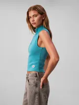 Musculosa Calvin Klein de corte slim confeccionada en tejido de punto de canalé fino. Presenta cuello perkins con cierre frontal parcial y etiqueta tejida con el logo monograma en el bajo.