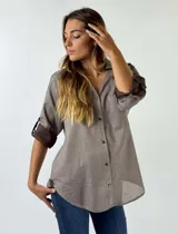 Camisa color marrón claro con cuello clásico, abotonada al frente, mangas 3/4 con puños en contraste marrón oscuro y bolsillo de parche en el pecho.