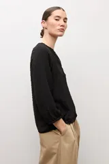 Blusa negra de manga larga con diseño de tejido plumeti y escote en V.