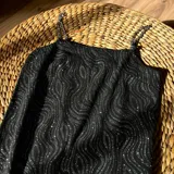 Vestido negro con estampado de ondas plateadas y tirantes de cadena metálica.