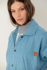 Campera de jean oversize color azul claro, con cuello camisero, cierre frontal con botones y bolsillos frontales. Presenta un diseño de corte amplio y cómodo con mangas largas.