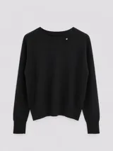 Suéter de tejido fino color negro, con cuello a la base y mangas largas. Presenta un pequeño detalle metálico en el escote y puños acanalados.