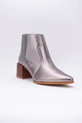 Botas cortas de cuero color beige, con punta fina y cierre lateral. Tienen un taco cuadrado de madera.