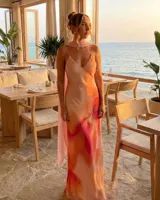 Vestido largo de seda con tirantes finos y escote en V, con un estampado abstracto en tonos rosados, naranjas y rojos. Incluye un pañuelo a juego que se anuda al cuello.