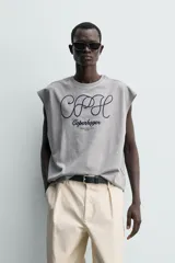 Camiseta sin mangas de corte relajado, color gris melange, con cuello redondo y estampa bordada en contraste en el frente.