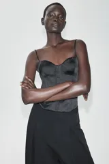 Top de satén negro estilo corsetero, con escote corazón, tirantes finos ajustables y cierre frontal con ganchos metálicos.