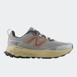 Championes de trail running New Balance Garoé V2, color gris con detalles en naranja y entresuela en tono arena. Presentan tecnología Fresh Foam X para amortiguación, suela AT Tread para tracción en diversos terrenos y refuerzos Toe Protect en la puntera.