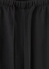 Pantalón de corte recto y largo, color negro, con cintura ajustable con cordón y bolsillos laterales.