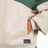 Canguro con capucha y cordones ajustables, diseño bicolor con bloque superior en verde y bloque inferior en beige. Presenta un pequeño estampado circular en el pecho con motivos de sol y texto. Posee puños y ruedo acanalados.