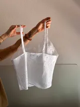 Top blanco de algodón con broderie, breteles finos y escote en V con puntilla.