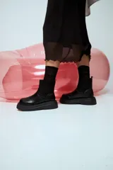 Botas tipo chunky de cuero sintético negro, con caña elastizada de tejido acanalado y suela gruesa dentada.