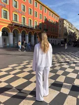 Camisa blanca de broderie con cuello camisero, mangas largas y cierre frontal con botones.