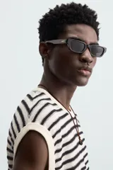 Camiseta sin mangas de punto con cuello redondo, tejido abierto a rayas horizontales negras y blancas, con ribetes en color crema.