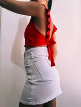 Crop top negro con textura brillante, breteles anchos con volados y espalda descubierta que se ata con lazos.