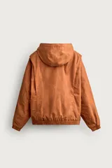 Cazadora de corte relajado para hombre, confeccionada en algodón con acabado efecto encerado en color marrón. Cuenta con cuello subido, capucha ajustable con cordones, mangas largas con puños elásticos y cierre frontal con cremallera. Incluye bolsillos frontales de vivo y forro interior a cuadros.