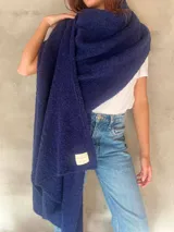 Chal de punto bouclé color marrón claro, hecho de 100% baby alpaca. Tejido suave, esponjoso y cálido, ofrece una textura envolvente y lujosa.