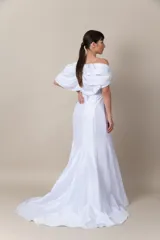 Vestido blanco de tafeta, strapless, con detalle de broche bordado en el escote. Presenta cinta trenzada en la espalda para ajustar y mangas caídas removibles. Vestido con cola.