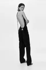 Top halter extralargo de punto elástico, color negro, con maxiescote drapeado, tiras finas para anudar al cuello y diseño asimétrico con fruncidos en los laterales.