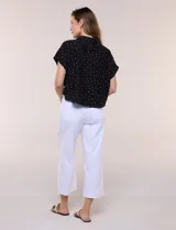 Blusa crop cruzada Allie Rose de tela liviana negra con estampado de lunares blancos, escote en V y cuello camisero.