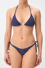 Top de bikini tipo triángulo en color azul marino con estampado de lunares blancos, tiras ajustables al cuello y a la espalda, y detalle de cuentas blancas en el centro.