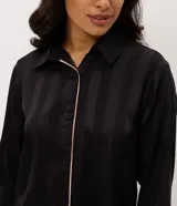 Pijama largo Lov de dos piezas confeccionado en satén negro con rayas sutiles y detalles de vivo en contraste. Consta de una camisa de manga larga con cuello y solapa, abotonado frontal, y un pantalón de calce amplio con cintura elastizada.