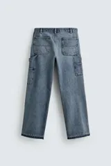 Pantalón de jean estilo carpintero con corte relaxed fit, tiro medio y pierna recta. Presenta un lavado azul medio con efecto desgastado y roturas en las rodillas. Incluye bolsillos laterales tipo plastrón, tira multifunción en la pierna, cierre frontal con cremallera y botón.