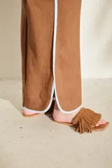 Pantalón azul marino de corte wide leg con detalles en tono marrón tostado en la cintura, bolsillos y bordes laterales, cuenta con trabillas para cinturón y cierre frontal.