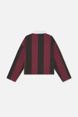 Polo de manga larga con rayas verticales en borgoña y negro, cuello de contraste blanco y cierre frontal parcial con botones ocultos. Presenta diversos bordados y parches decorativos en el pecho.