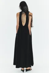 Vestido midi de corte fluido, cuello redondo y diseño sin mangas. Presenta una abertura en la espalda con cierre de lazada ajustable.