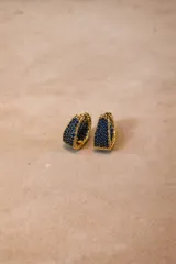 Aros tipo argolla con base metálica dorada e incrustaciones de cristales negros en toda su superficie frontal.