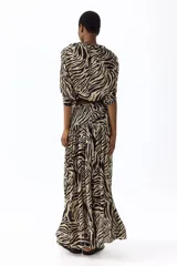 Pollera maxi de tiro alto confeccionada en gasa con estampado de cebra en tonos beige y negro. Cuenta con cintura ancha y costura fruncida en diagonal.