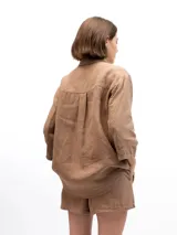 Camisa unisex de lino con mangas tres cuartos, cuello clásico, cierre frontal con botones y un bolsillo aplicado en el pecho.