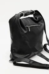 Cartera convertible en mochila, confeccionada en cuero sintético texturizado color marrón. Presenta un diseño con recortes, bolsillo frontal con cierre diagonal, herrajes metálicos plateados, asa superior y correas regulables.