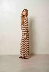 Vestido largo de lurex con diseño de patrón en zigzag en tonos tostado y marrón, escote en V con cordones para atar y mangas largas.