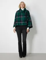 Capa de tejido cuadrille con diseño de cuadros en tonos marrón, beige y naranja. Presenta un cierre frontal con botón tipo trenca y bordes con ribete negro.