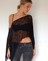 Capa de encaje negro con diseño asimétrico y caída holgada, ideal para usar sobre otras prendas.