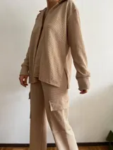 Camisa tejida color beige, de manga larga y corte holgado.