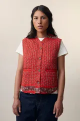 Chaleco sin mangas de algodón acolchado con estampado floral en tonos rojos y marrones. Tiene cuello camisero, cierre frontal con botones de madera y bolsillos de parche. El modelo Patchwork Tomette está tejido a mano.