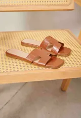 Sandalias planas blancas de diseño destalonado, con pala ancha troquelada y suela baja.