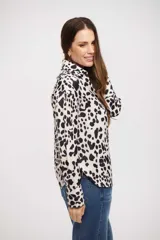 Camisa de manga larga con cuello clásico y cierre frontal de botones. Presenta un estampado de manchas tipo animal print en tonos blanco y negro.