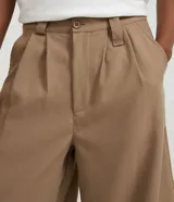 Bermuda masculina color beige, corte amplio, de viscosa y poliéster. Presenta cintura con trabillas, cierre tradicional y bolsillos laterales.